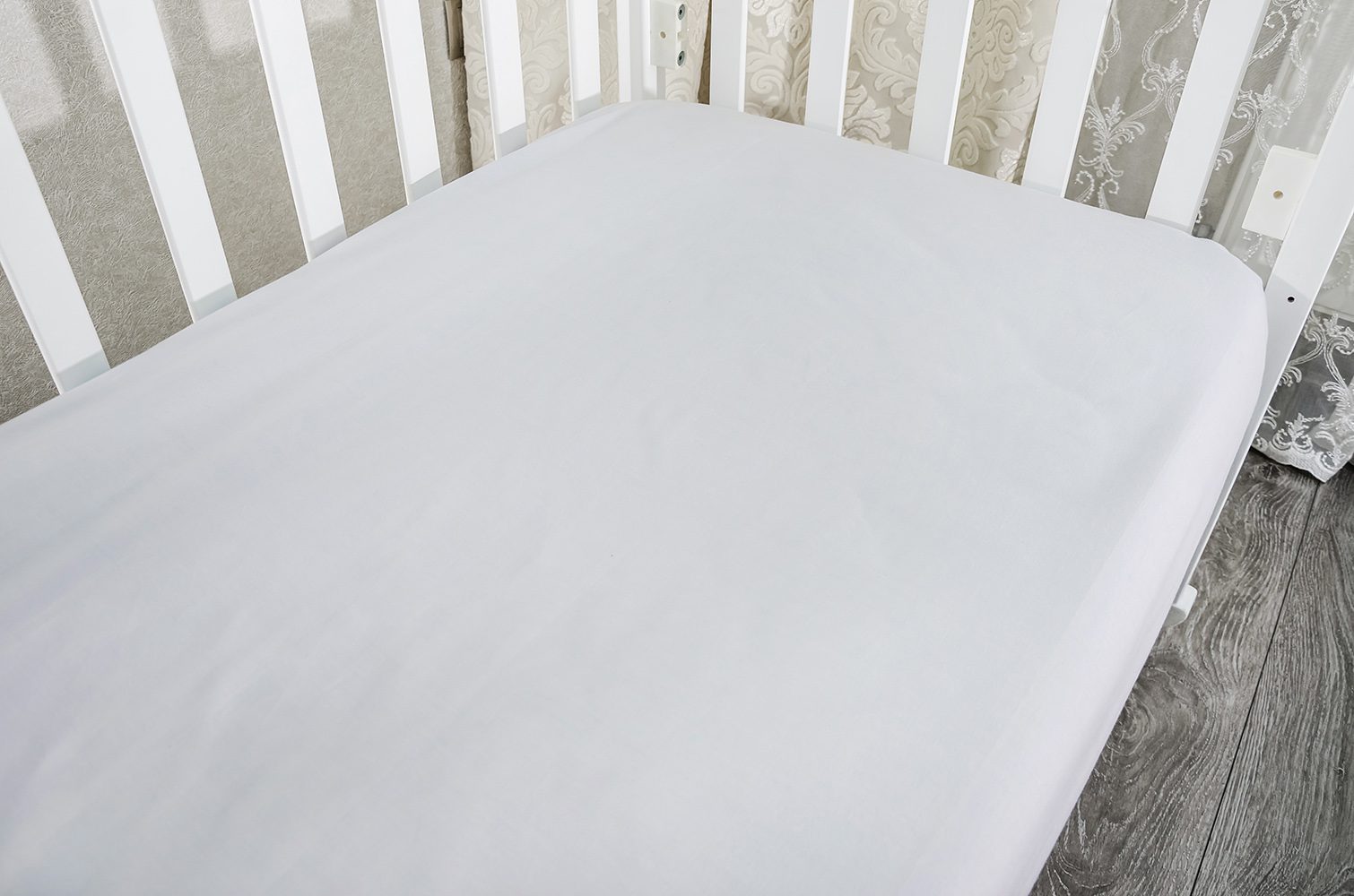 part of baby cot, close up. Mattress and sheets in white crib.