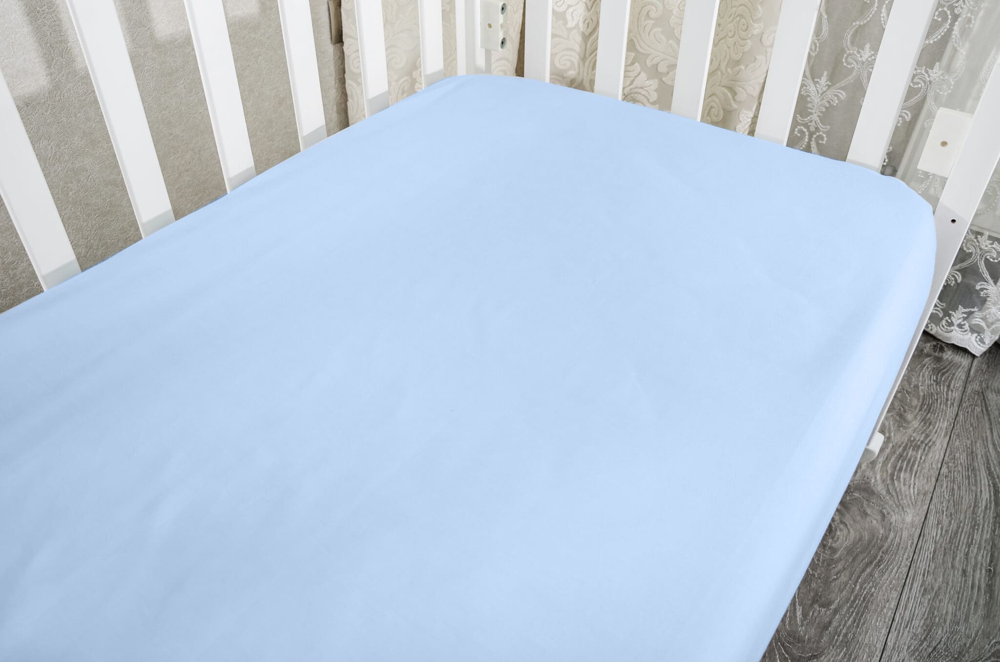 part of baby cot, close up. Mattress and sheets in white crib.