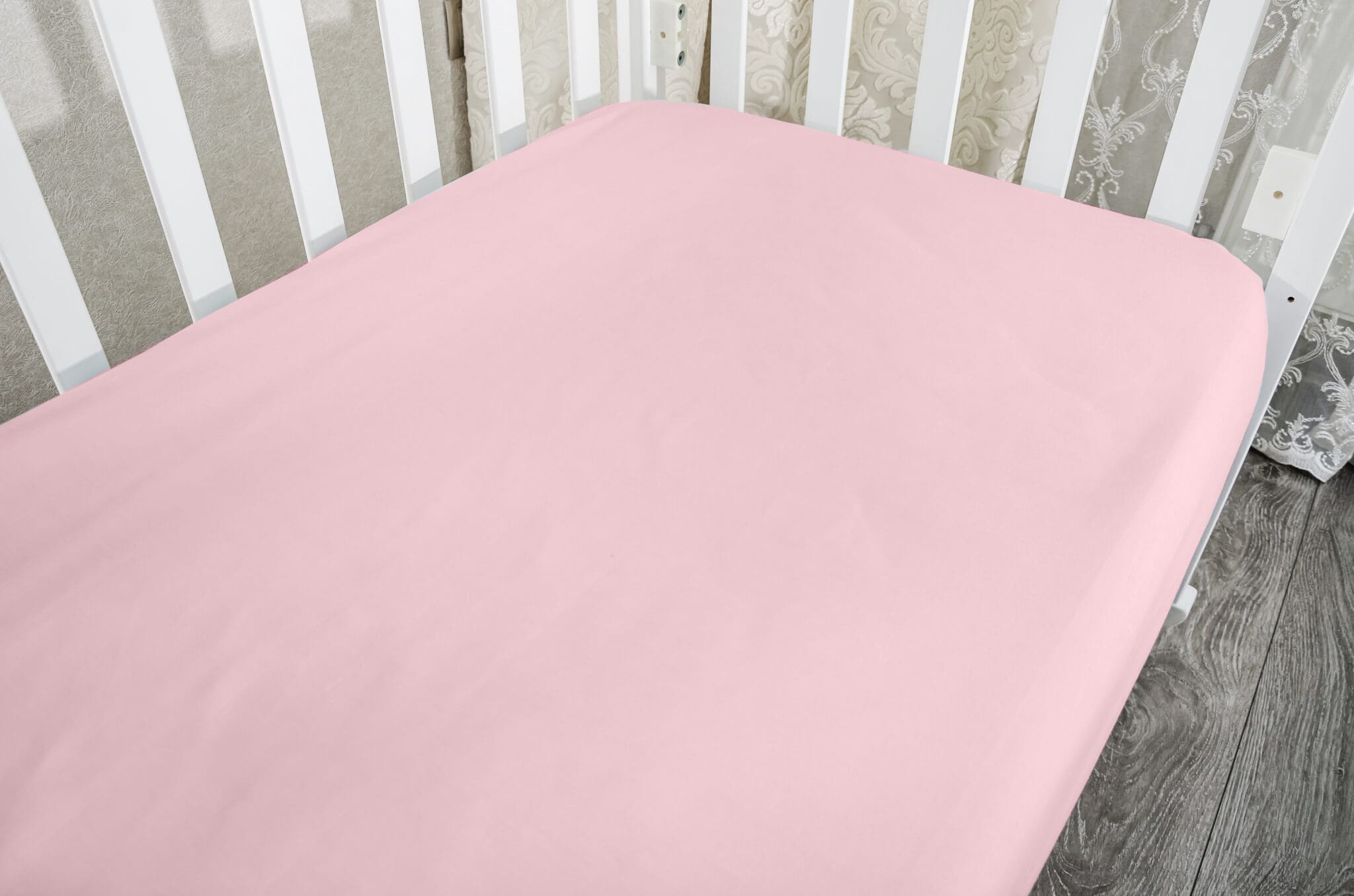 part of baby cot, close up. Mattress and sheets in white crib.